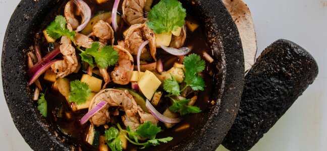 Aguachile negro with shrimp, cucumber, red onion, mango and cilantro in a black molcajete